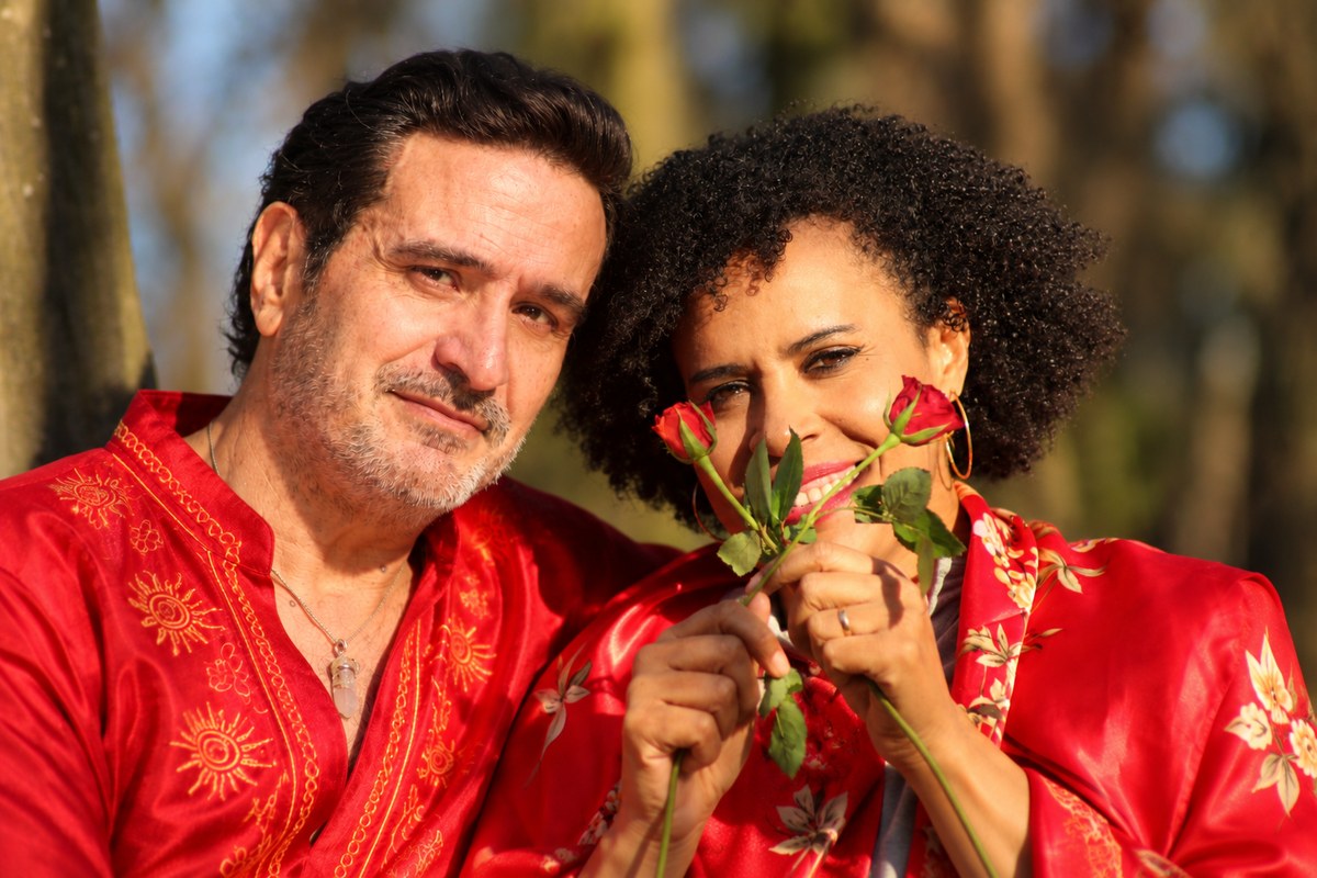 Ayam e Ayala de vermelho, sorrindo, ela segurando duas rosas vermelhas diante do rosto