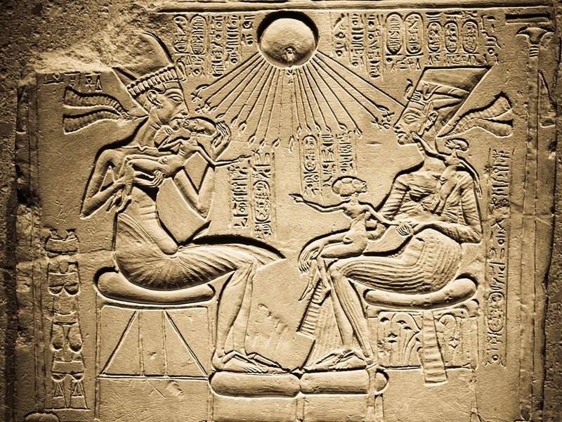 Relevo egípcio de Akhenáton e Nefertiti sentados frente a frente com três filhas, sob os raios do disco solar